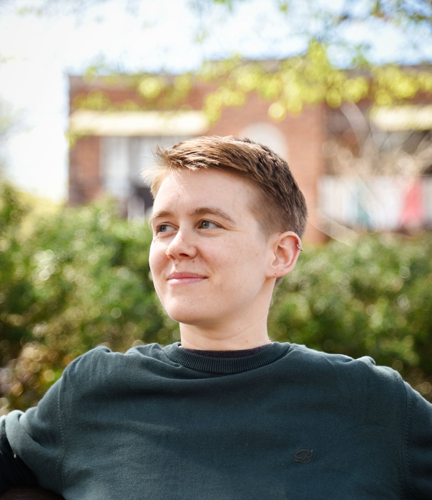 Portrait of Fil, looking off to the side and smiling, in a dark green sweater.